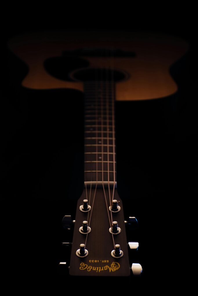 zipwp-image-1202130 Artistic close-up of an acoustic guitar neck with focus on the headstock under soft lighting.